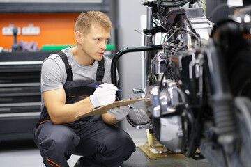 A motorcycle repairman takes notes, close-up