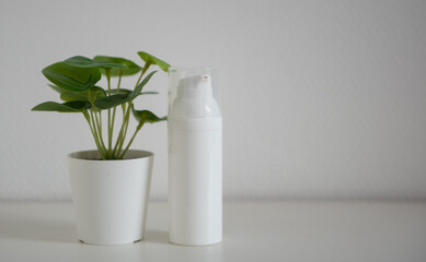 Flacon cosmétique blanc sur fond blanc avec plante verte - mock up 