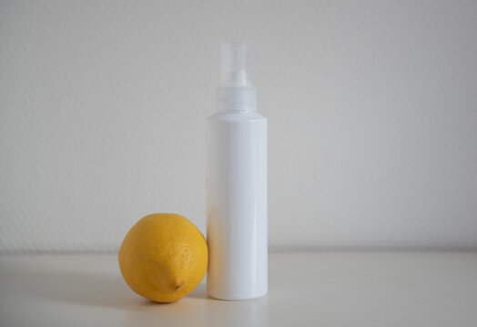 Flacon cosmétique blanc sur fond blanc avec citron jeune - mockup produit de beauté avec citron