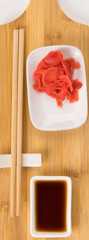 ginger and soy sauce with a set of accessories for eating sushi and rolls on a wooden board