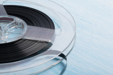 an old magnetic tape on a reel lies on a white blue background