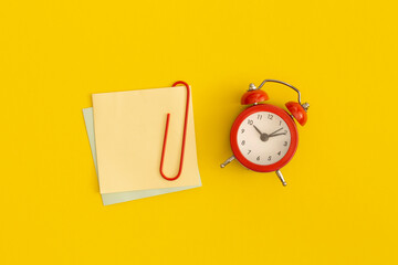 Red alarm clock and sticky notes with space for text on yellow background