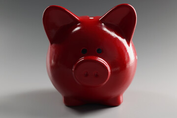 Red ceramic piggy bank on a gray background, close-up