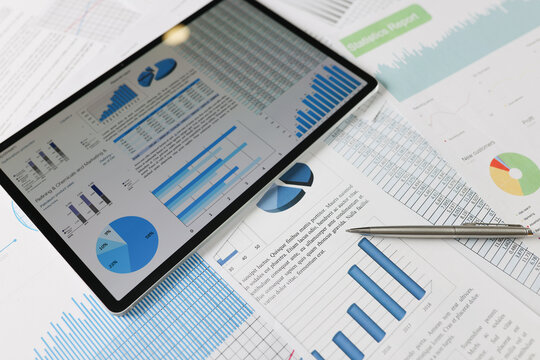 On statistical reports lies a tablet with charts on the screen