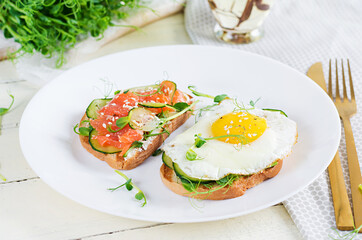 Diet breakfast. Sandwich with salt salmon salad with greens, cucumbers, fried egg and microgreen.