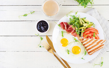 English breakfast - fried egg, jamon, toast and fresh vegetables salad. Top view, overhead