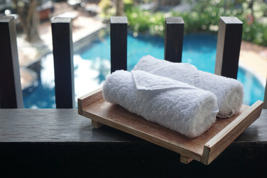 A Small White Towel Neatly Rolled Up On A Wooden Plank In A Pool Background                                 