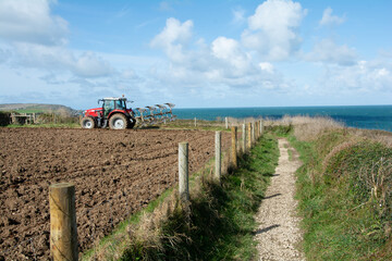 October 2019 - A farmer ploughs his field on a coastal farm at Trevose Head in Cornwall, UK