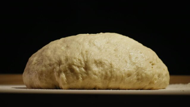 Timelapse yeast dough increases in size on a table against a dark background