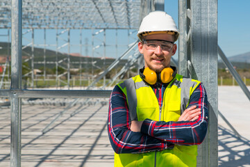 Cheerful construction worker smiling at the camera while sitting. Handsome young man, sitting in front of framework of the new building.