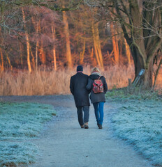 Winterspaziergang eines Ehepaares in einem einem Wald bei Sonnenaufgang