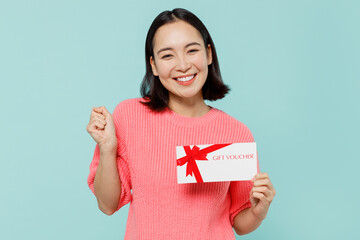 Young smiling happy cool woman of Asian ethnicity 20s wearing pink sweater hold gift certificate...