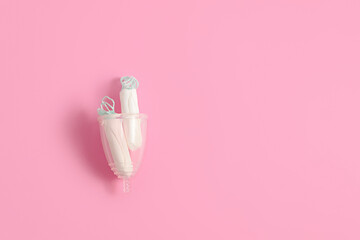 Tampons vs menstrual cup on pink background. Concept of alternative protection during critical days