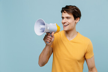Young smiling happy fun man 20s wear yellow t-shirt hold scream in megaphone announces discounts...