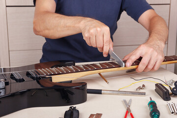 Guitar repairman crowning frets on guitar neck with fret files.