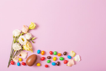 easter chocolate eggs and flowers on color paper background