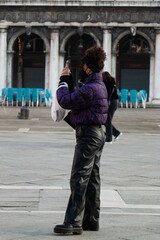 Naklejka premium A young woman in black faux leather pants and a black and purple jacket.