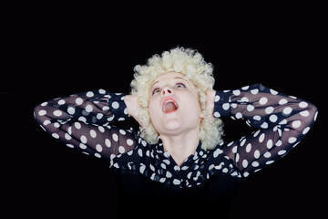 Curly girl - blonde in a blouse with polka dots like a clown screams on a black background