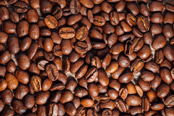 Roasted coffee beans on dark brown wooden table. Top view on coffee beans on wooden background.