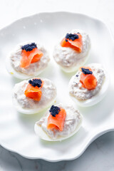 boiled eggs filled with tuna fish spread and smoked salmon and  black caviar on the top