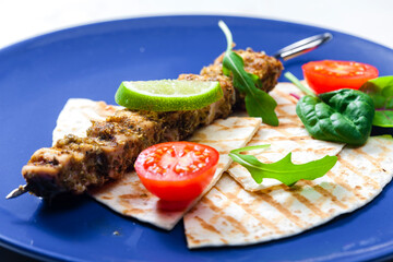 herbal meat skewer  with pita bread, tomatoes and lime