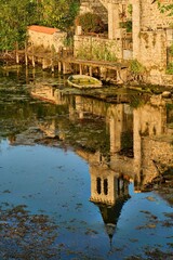 the church of Sanxay is reflected in the water surface of the Vonne where a sunken rowing boat is floating