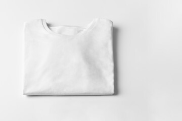 Basic folded white Tshirt on grey table with copy space. Mock up for branding t-shirt. Monochrome...