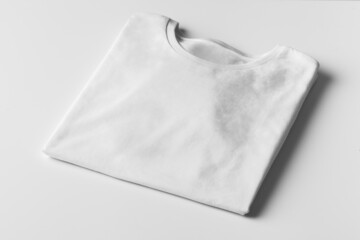 Basic folded white Tshirt on grey table with copy space. Mock up for branding t-shirt. Monochrome...