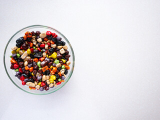 Sweets in a glass plate on a white background. Multicolored sea stones