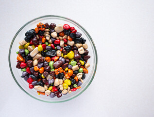 Sweets in a glass plate on a white background. Multicolored sea stones