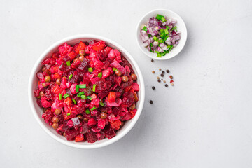 A bowl with beetroot vegetable salad on a gray background with onions and herbs.