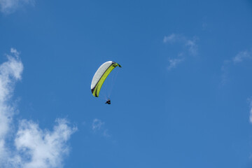 Paragliding pilot in the air with blue sky and white clouds, near the Wasserkuppe nature park Rhön Germany.