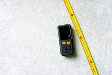 Classic mechanical tape measure and laser tape measure on a concrete background.