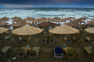 Strom at the beach. Big waves  and cloudy sky. Wooden umbrellas and empty beach