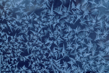 Frost draws: a pattern of different elements on the window glass on a frosty morning, close-up, blue color