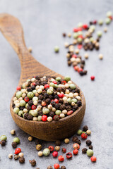 Peppercorn mix in a wooden bowl on grey table.