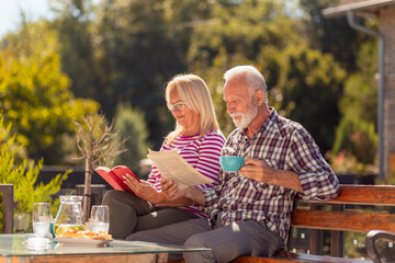 Senior couple drinking coffee outdoor and reading