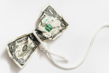 White rope tangled around a crumpled one dollar bill.