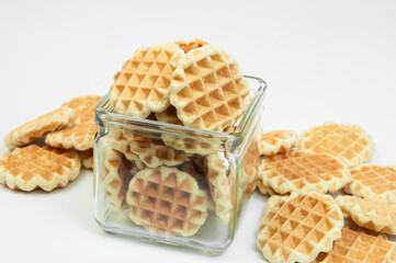 cookies in a glass jar on a white background. Belgian waffles in a bowl. fresh baking concept.