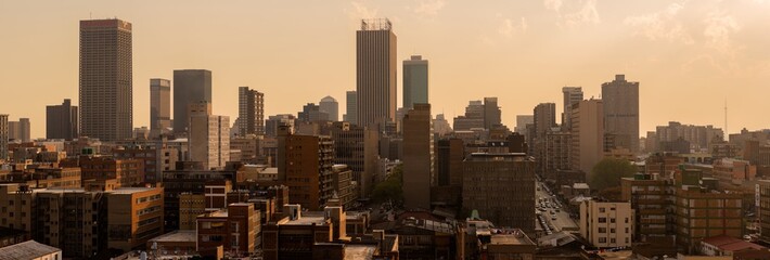 Naklejka premium A horizontal panoramic cityscape taken at sunset, of the central business district of the city of Johannesburg, South Africa