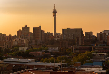 Obraz premium A horizontal panoramic cityscape taken during a golden sunset, of the central business district of the city of Johannesburg, South Africa