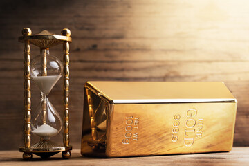 Hourglass with pouring sand and a heavy shiny gold bar.