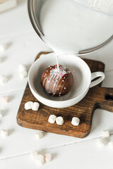 close up of a cup of coffee with whipped cream and a glass of milk on a white wooden background