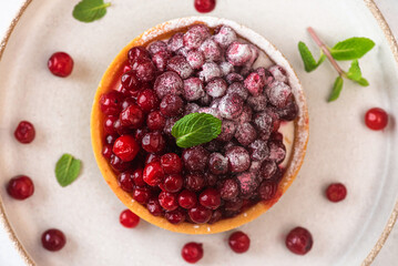 Berry tart. French pastry cakes with cowberry, powdered sugar and mint in a plate. Top view. Close up