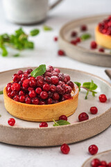 Berry tart. French pastry cakes with cowberry, powdered sugar and mint. Tasty dessert