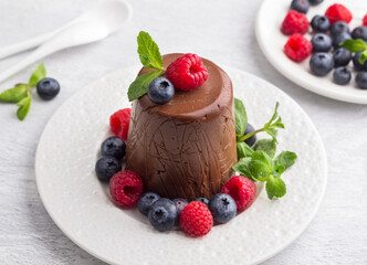 Vegan cashew and chocolate Easter paskha, delicious dessert with berries and mint on light blue background