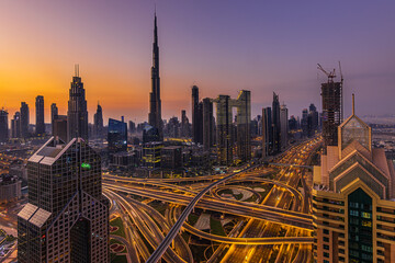 Fototapeta na wymiar Dubai skyline in the morning. Skyscrapers in downtown Dubai with sunrise. reddish orange colors sky. Road crossing with illuminated lane. Commercial buildings and apartments in the center of Dubai