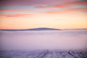 Fototapeta premium moody winter landscape with fog at sunset