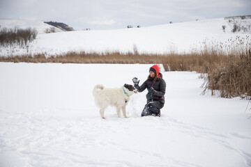 woman and her happy white dog enjoying winter snow outdoors on sunny day