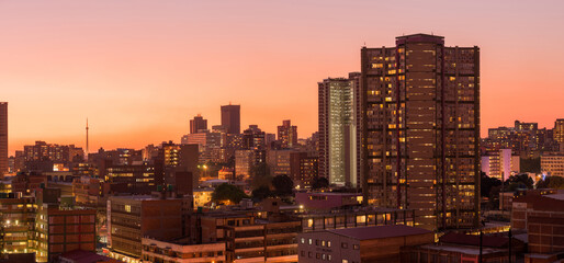 Obraz premium A horizontal panoramic cityscape taken during a golden sunset, of the central business district of the city of Johannesburg, South Africa